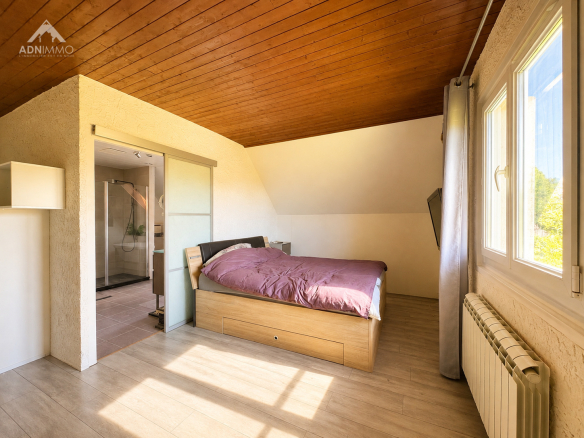Chambre lumineuse avec lit double et fenêtres, maison à Crozet.