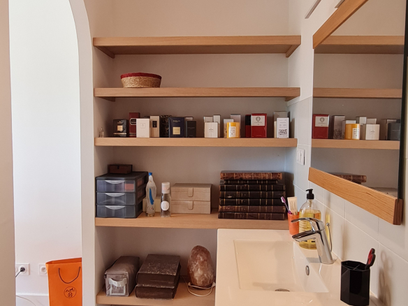 Interior of a bathroom with shelves and sink.