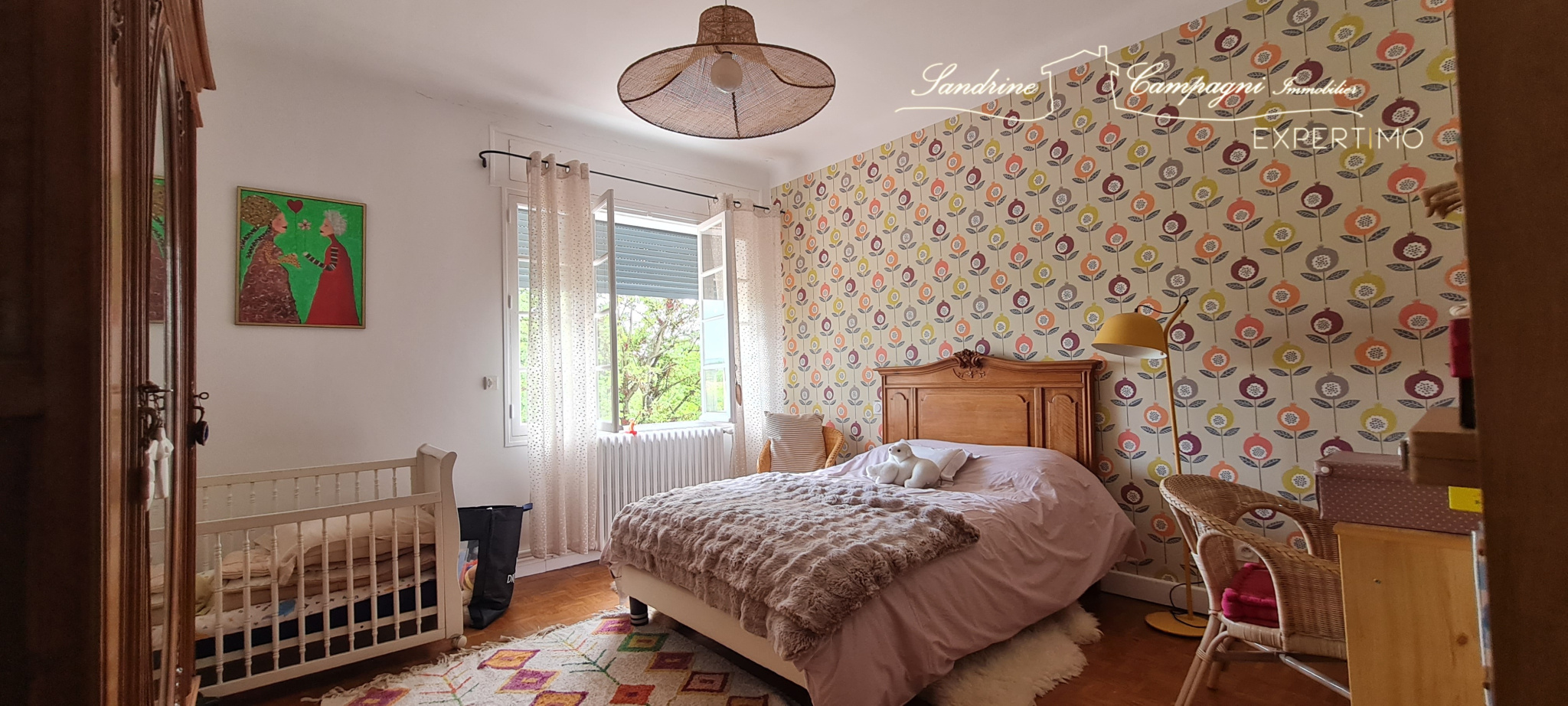 Bedroom in a renovated house with a double bed and a baby cot, decorated with colorful wallpaper.