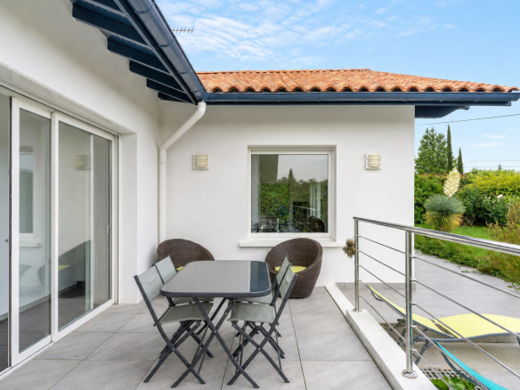 Terrasse d'une propriété familiale à Urrugne avec mobilier de jardin et vue sur le jardin.