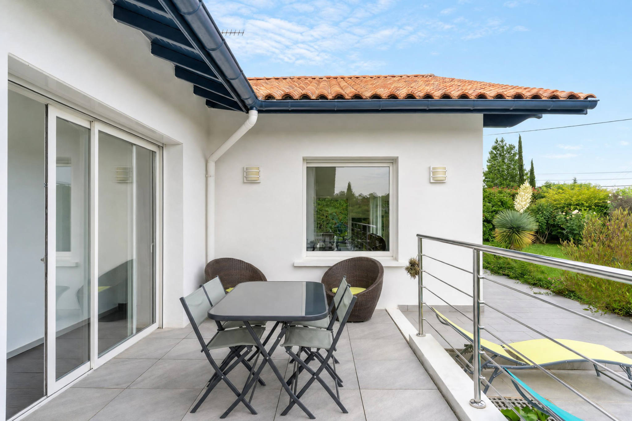 Terrasse de la propriété familiale à Urrugne Terrasse d'une propriété familiale à Urrugne avec mobilier de jardin et vue sur le jardin.