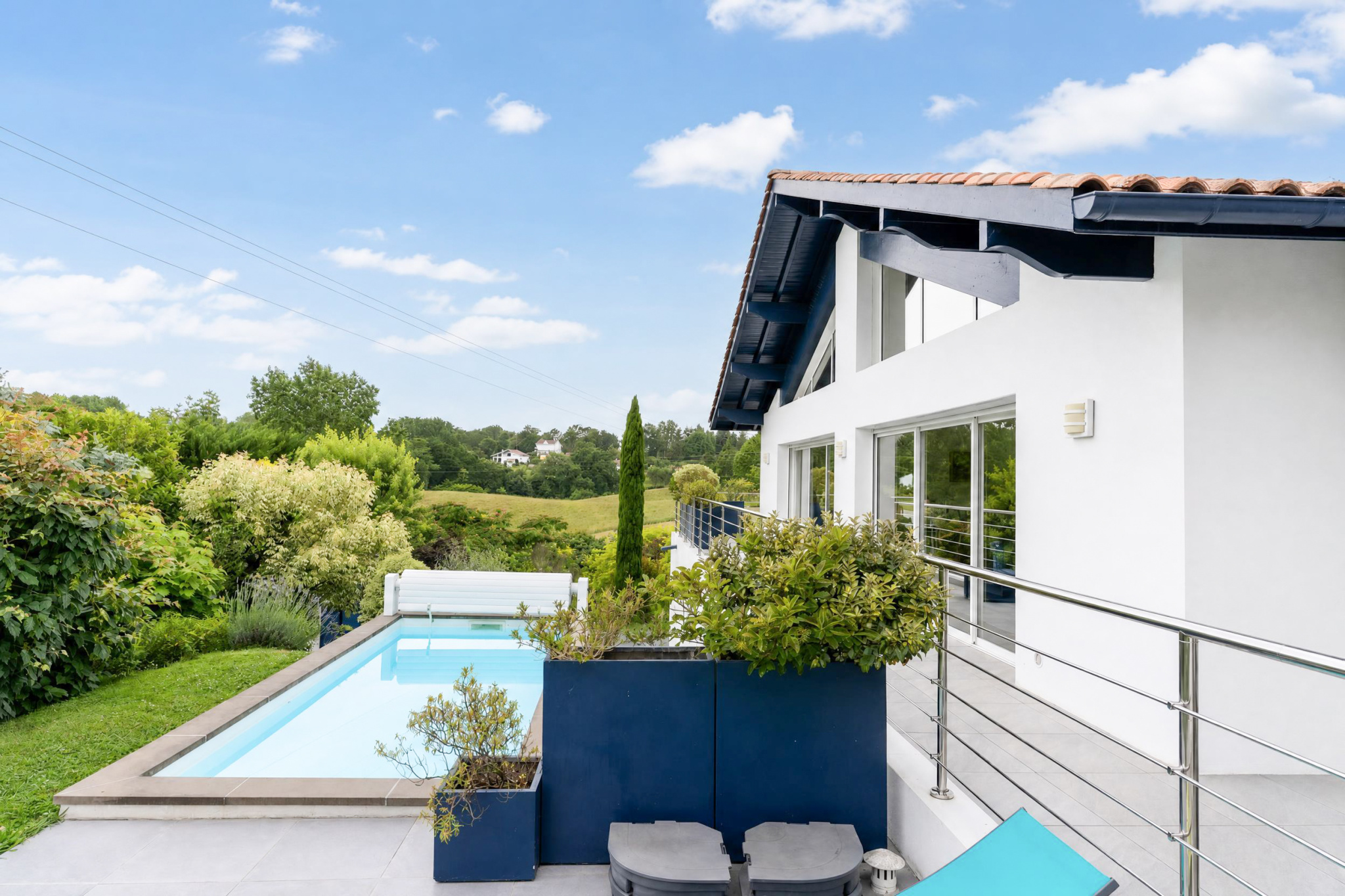 Propriété familiale à Urrugne Vue de la piscine et de la maison moderne avec jardin à Urrugne, ensoleillée et verdoyante.