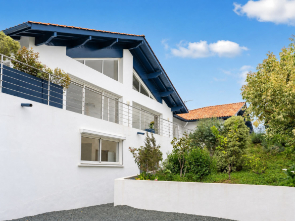 Vue extérieure d'une propriété familiale à Urrugne avec jardin et piscine.