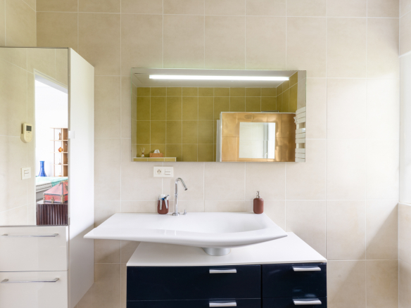 Salle de bain moderne avec lavabo design et miroir lumineux.