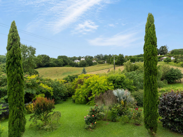 Vue d'un jardin paysagé avec des arbres et une pelouse verte à Urrugne.