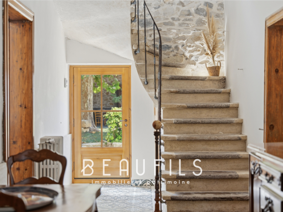 Intérieur d'une maison de maître vigneronne avec escalier en pierre et porte donnant sur le jardin.