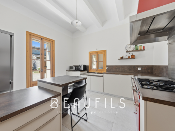 Cuisine moderne d'une maison de maître vigneronne à Vergèze, avec meubles contemporains et fenêtres ouvertes.