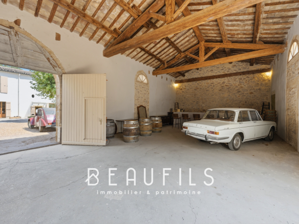 Intérieur d'un garage avec une voiture ancienne et des tonneaux en bois.