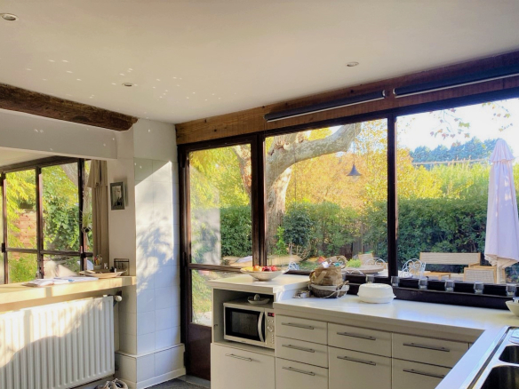 Intérieur d'une cuisine lumineuse avec vue sur un jardin, mas rénové dans le Luberon.
