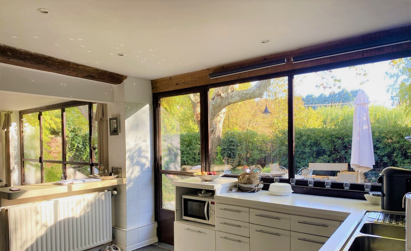 Cuisine d’un mas rénové dans le Luberon Intérieur d'une cuisine lumineuse avec vue sur un jardin, mas rénové dans le Luberon.