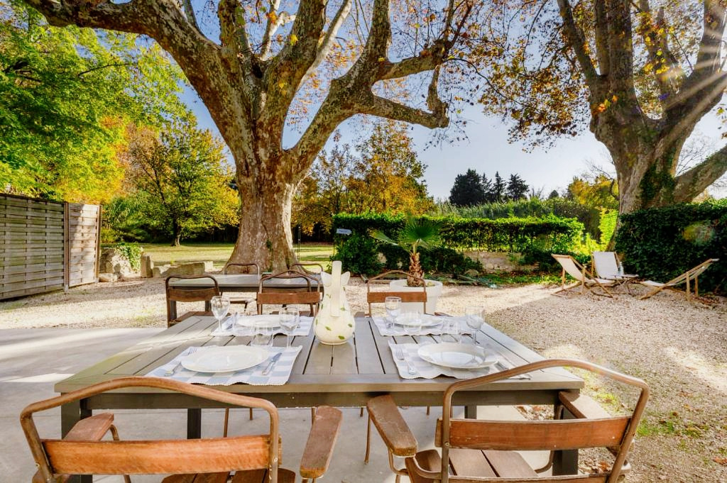 Table en extérieur au Mas de charme Table en bois dressée pour un repas en extérieur sous des arbres dans un parc.