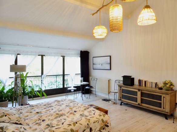 Chambre spacieuse avec lit, plantes et mobilier en bois dans un mas rénové.