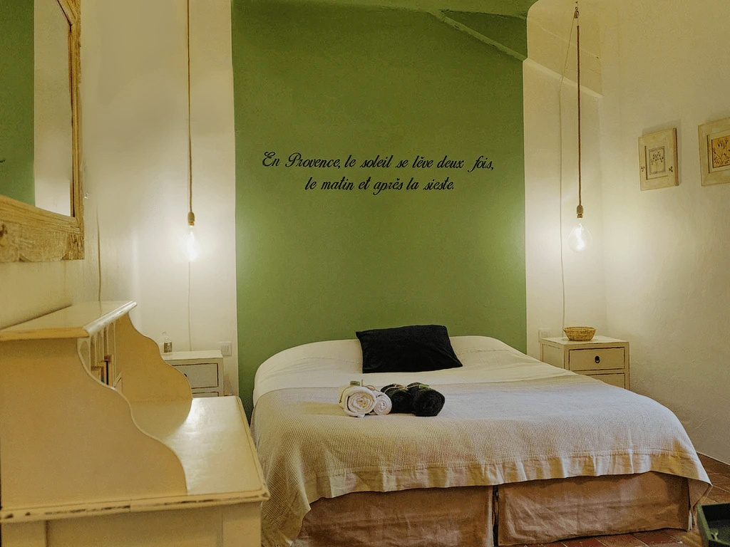 Chambre d’un mas rénové Chambre d'un mas rénové avec lit, décoration sobre et mur vert.