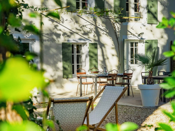 Mas rénové avec chaises et tables en extérieur, entouré de verdure, près de L'Isle-sur-la-Sorgue.