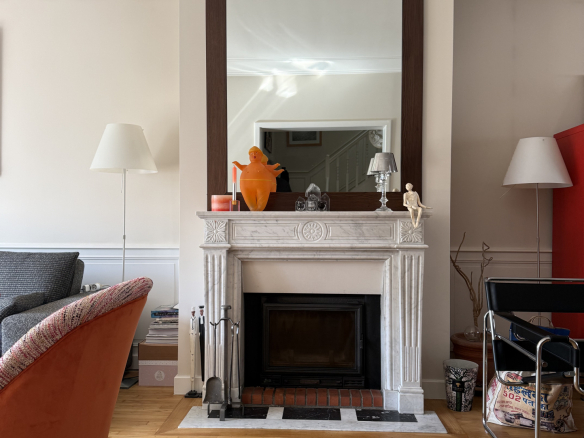 Intérieur d'une maison de caractère avec cheminée en marbre et miroir, salon lumineux.
