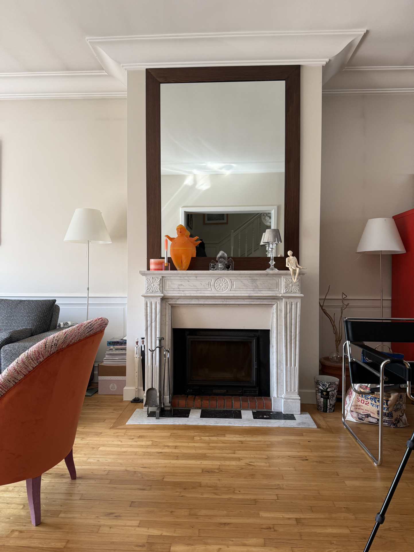 Intérieur d'une maison de caractère avec cheminée en marbre et miroir, salon lumineux.