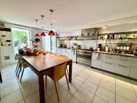 Cuisine moderne avec table en bois et chaises colorées, fenêtres donnant sur le jardin.