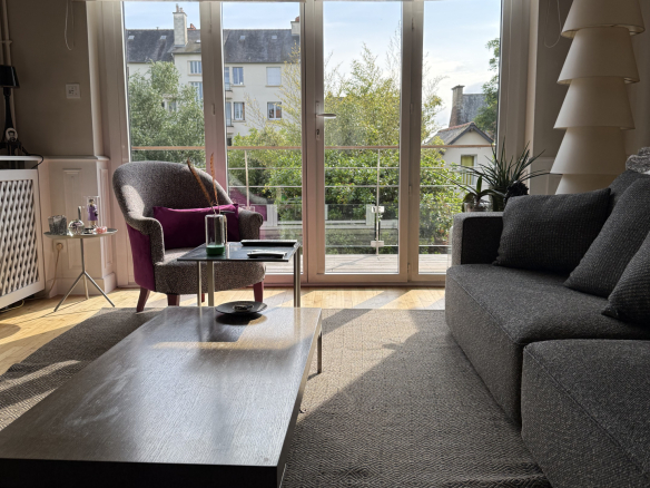 Salon lumineux avec vue sur jardin, mobilier moderne, fenêtres ouvertes sur l'extérieur.