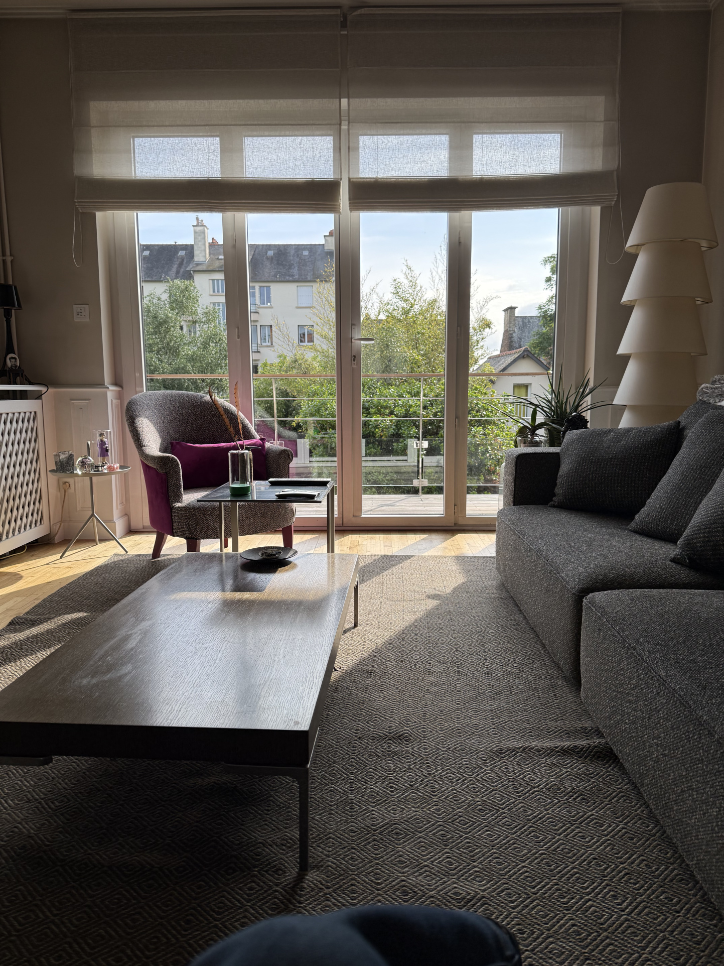 Salon lumineux avec vue sur jardin, mobilier moderne, fenêtres ouvertes sur l'extérieur.