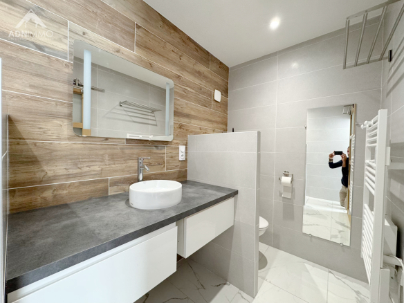 Salle de bain moderne avec lavabo, miroir et douche dans une maison à Farges.