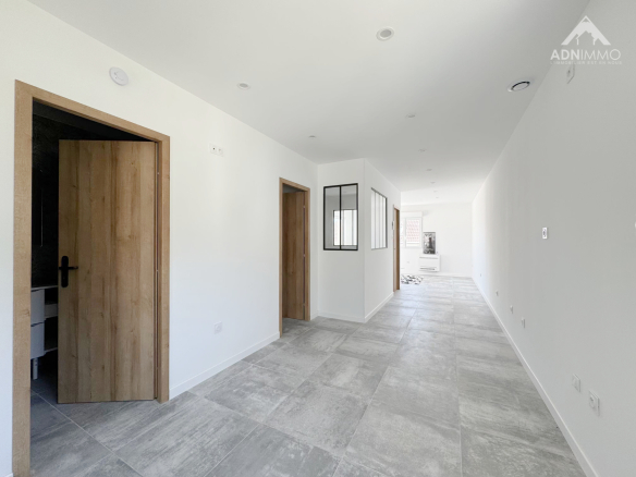 Intérieur d'une maison moderne à Farges, avec couloir lumineux et portes en bois.