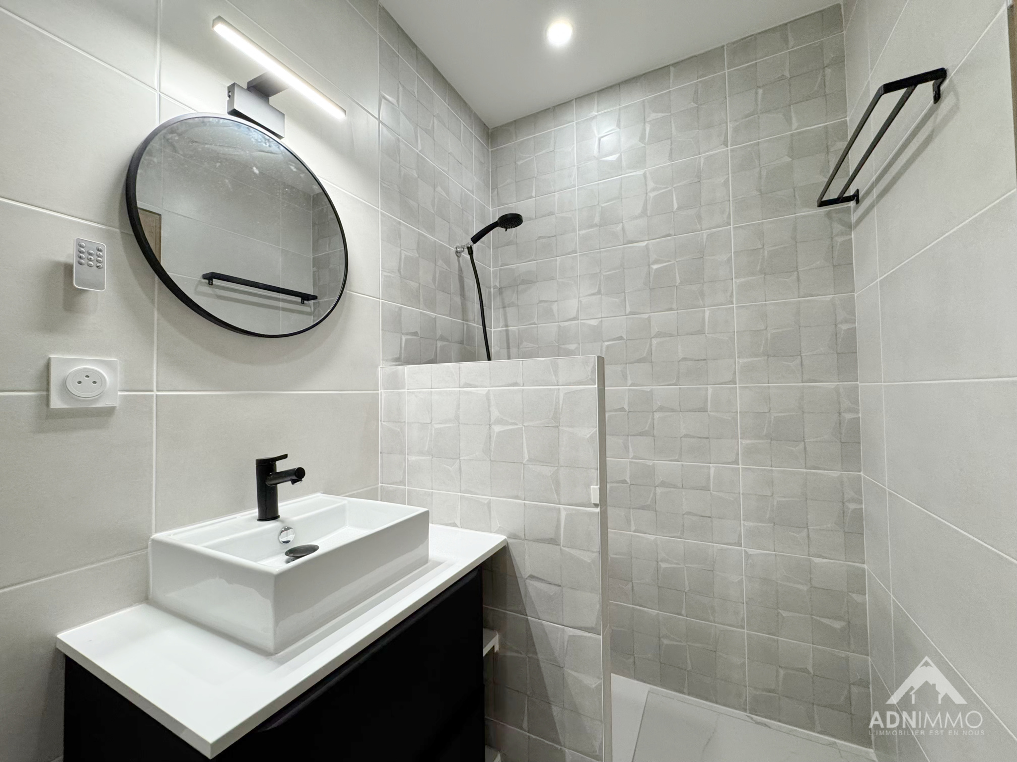 Salle de douche contemporaine Salle de douche moderne avec carrelage gris et lavabo noir.