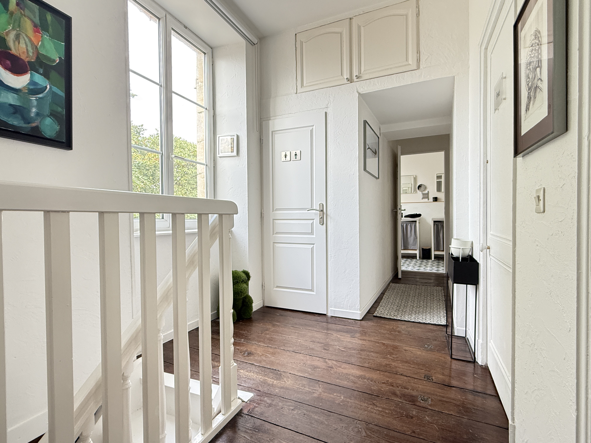 Intérieur d'une maison de caractère du XVIIIe siècle avec un hall d'entrée lumineux et des murs blancs.