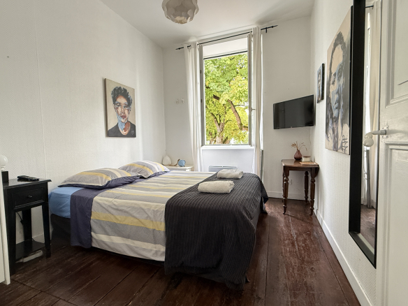 Chambre d'une demeure de caractère avec lit double, tableaux aux murs et fenêtre donnant sur l'extérieur.