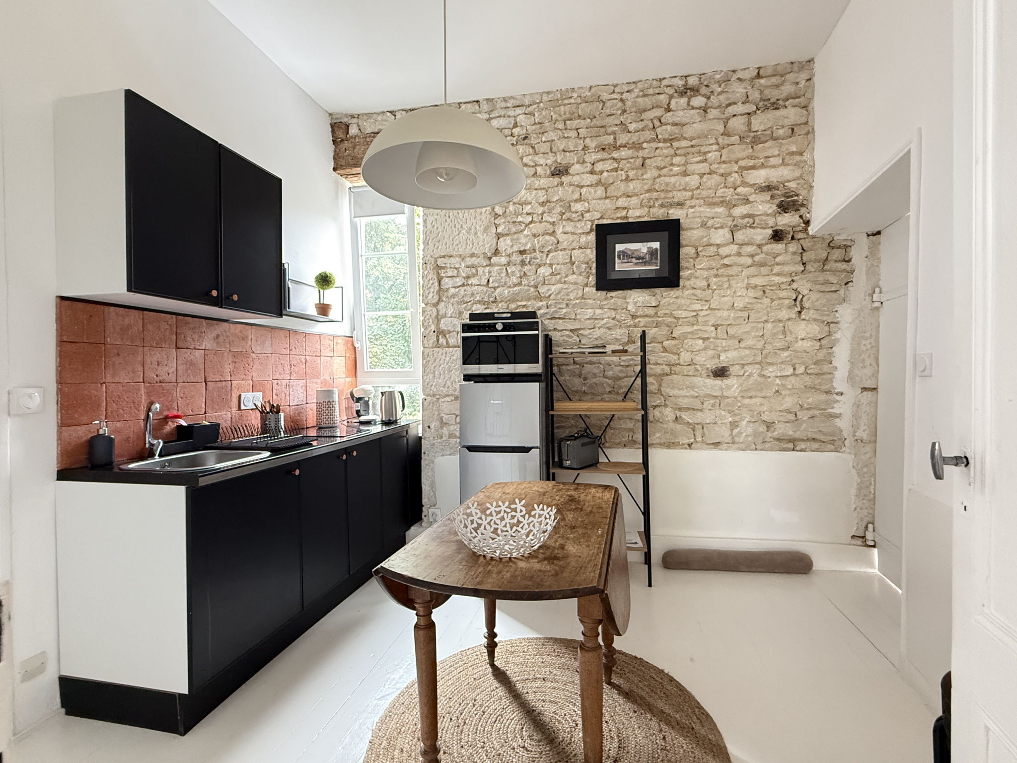 Cuisine rénovée avec murs en pierre et mobilier moderne dans une demeure du XVIIIe siècle.