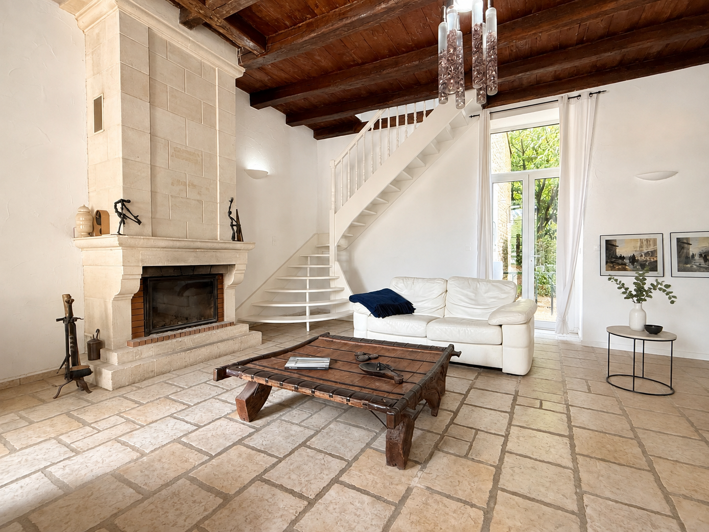 Intérieur d'une demeure du XVIIIe siècle avec un salon lumineux, cheminée en pierre et escalier en colimaçon.