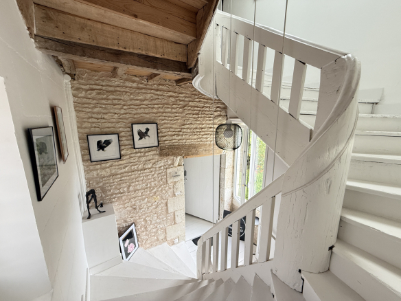 Escalier en colimaçon dans une maison ancienne avec murs en pierre et décoration murale.