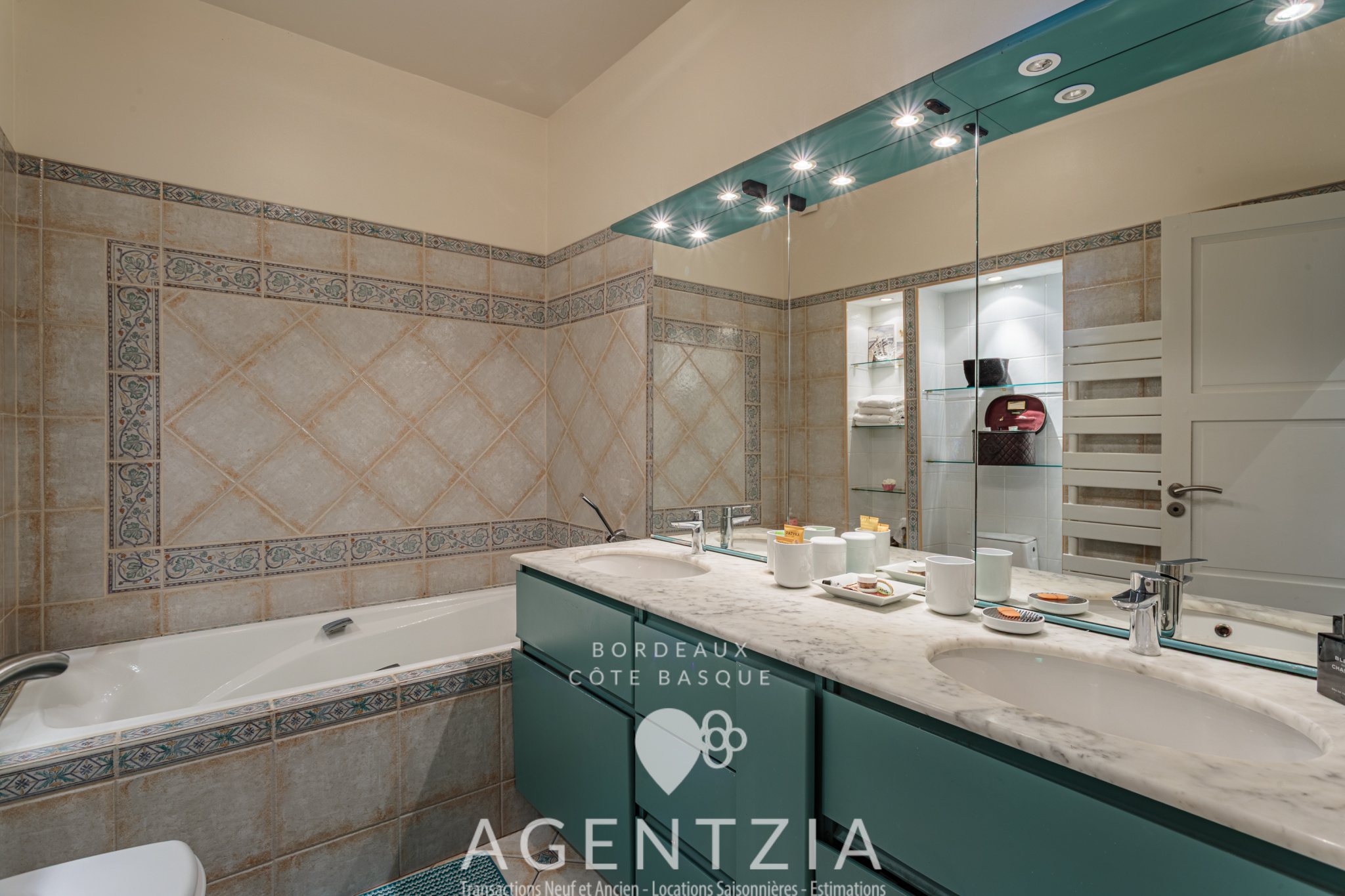 Salle de bain de l’appartement à Bidart Salle de bain moderne avec baignoire, lavabo et miroir éclairé dans un appartement à Bidart.