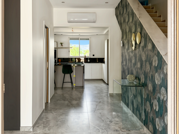 Intérieur d'une maison rénovée avec un hall d'entrée moderne et une cuisine ouverte.