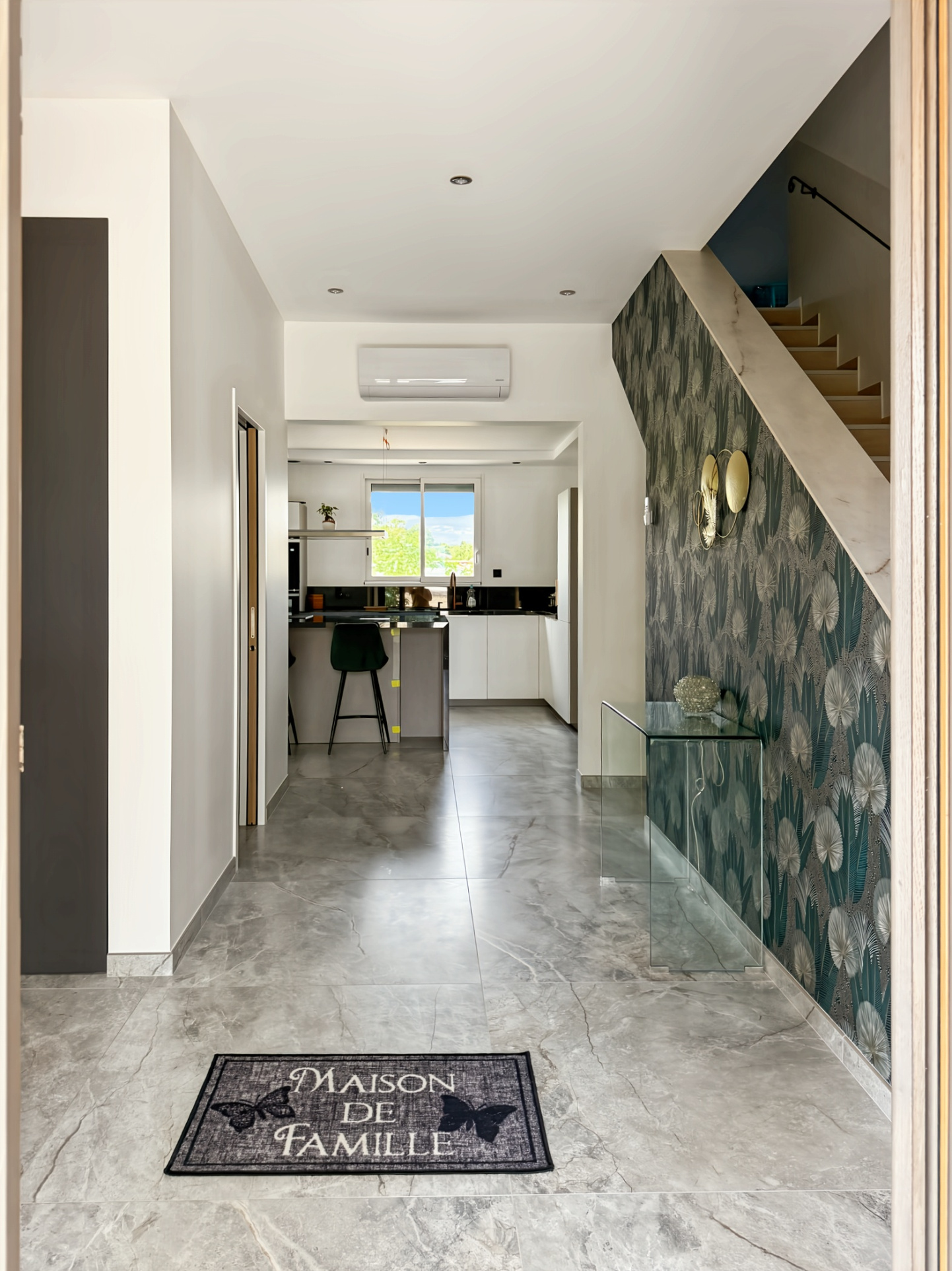 Intérieur d'une maison rénovée avec un hall d'entrée moderne et une cuisine ouverte.