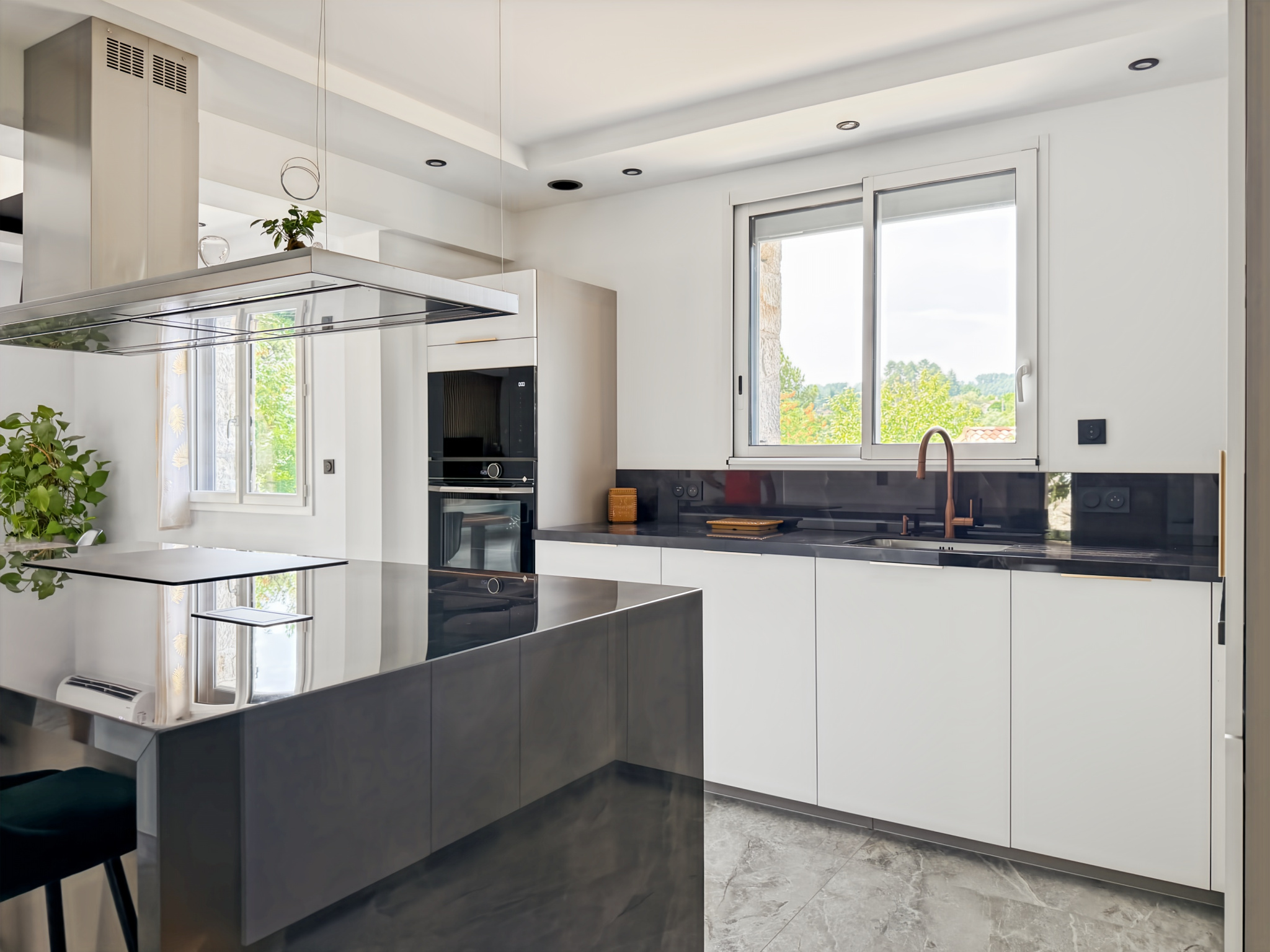 Cuisine moderne et lumineuse d'une maison rénovée avec îlot central et équipements contemporains.