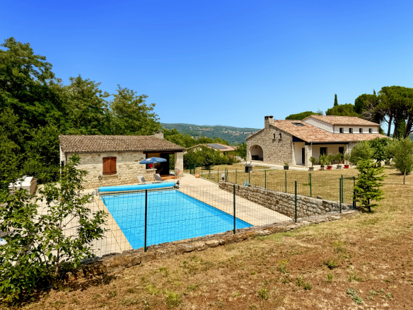 Maison en pierre rénovée avec piscine et terrain arboré à Joyeuse, vue dégagée.