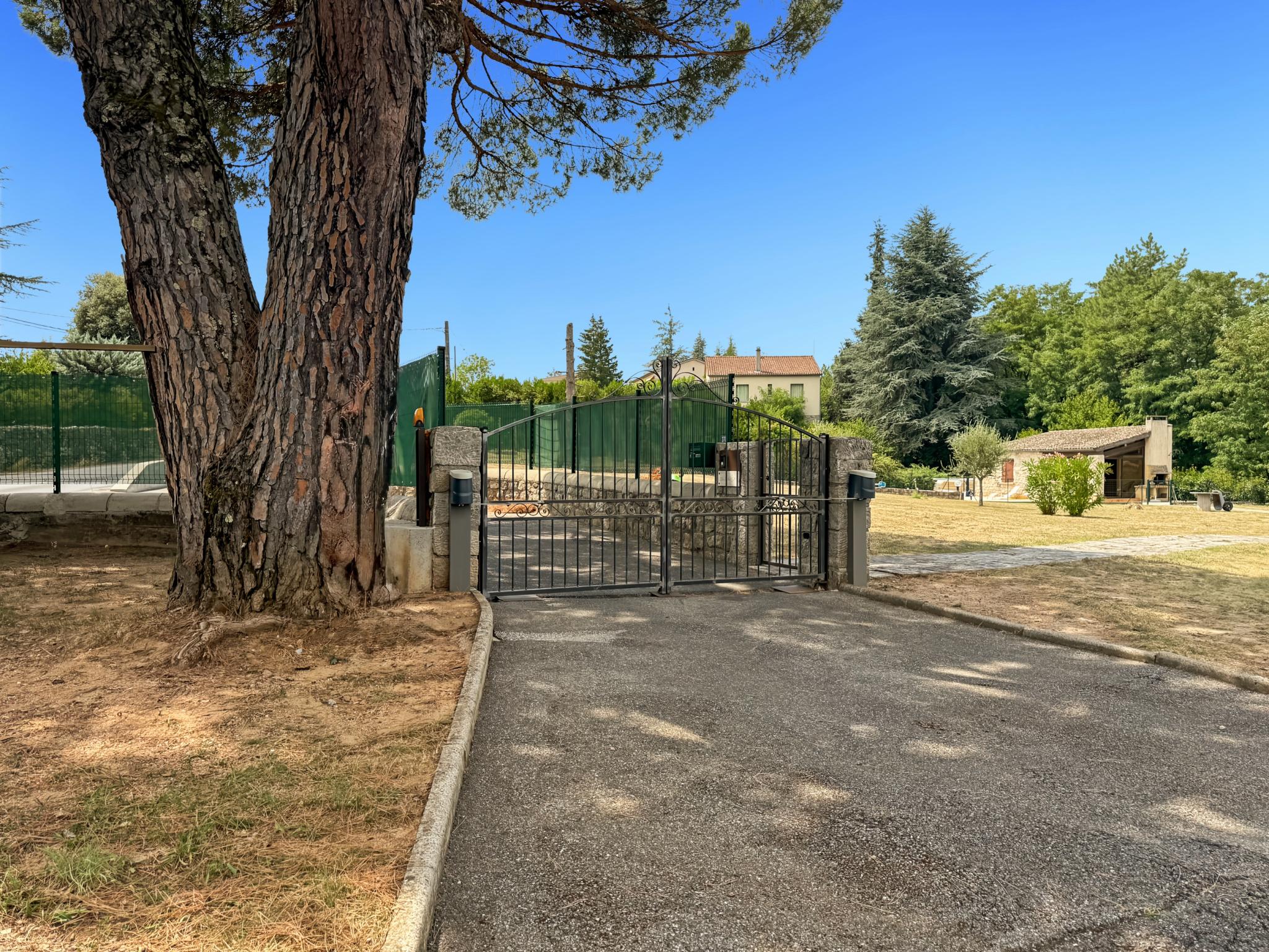Entrée d'une propriété avec portail, arbres et terrain arboré à Joyeuse.