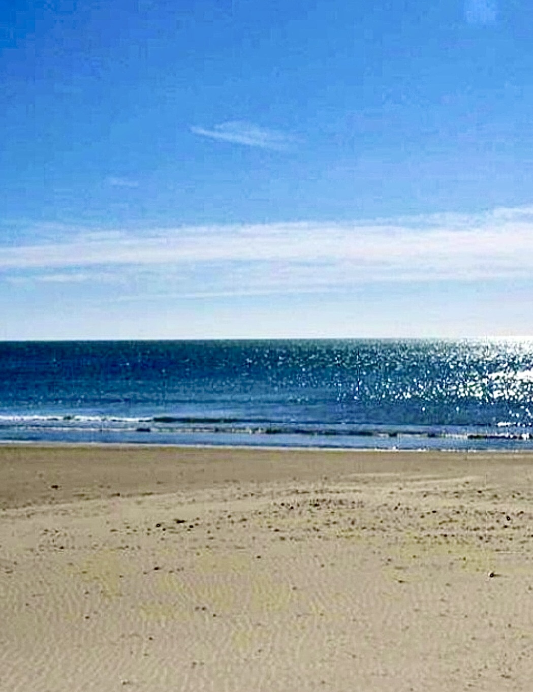 Plage de Carnon avec vue sur la mer Méditerranée sous un ciel ensoleillé.