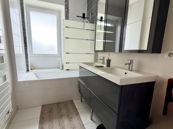 Salle de bain moderne avec baignoire, lavabo et miroir, dans une maison rénovée à Auray.