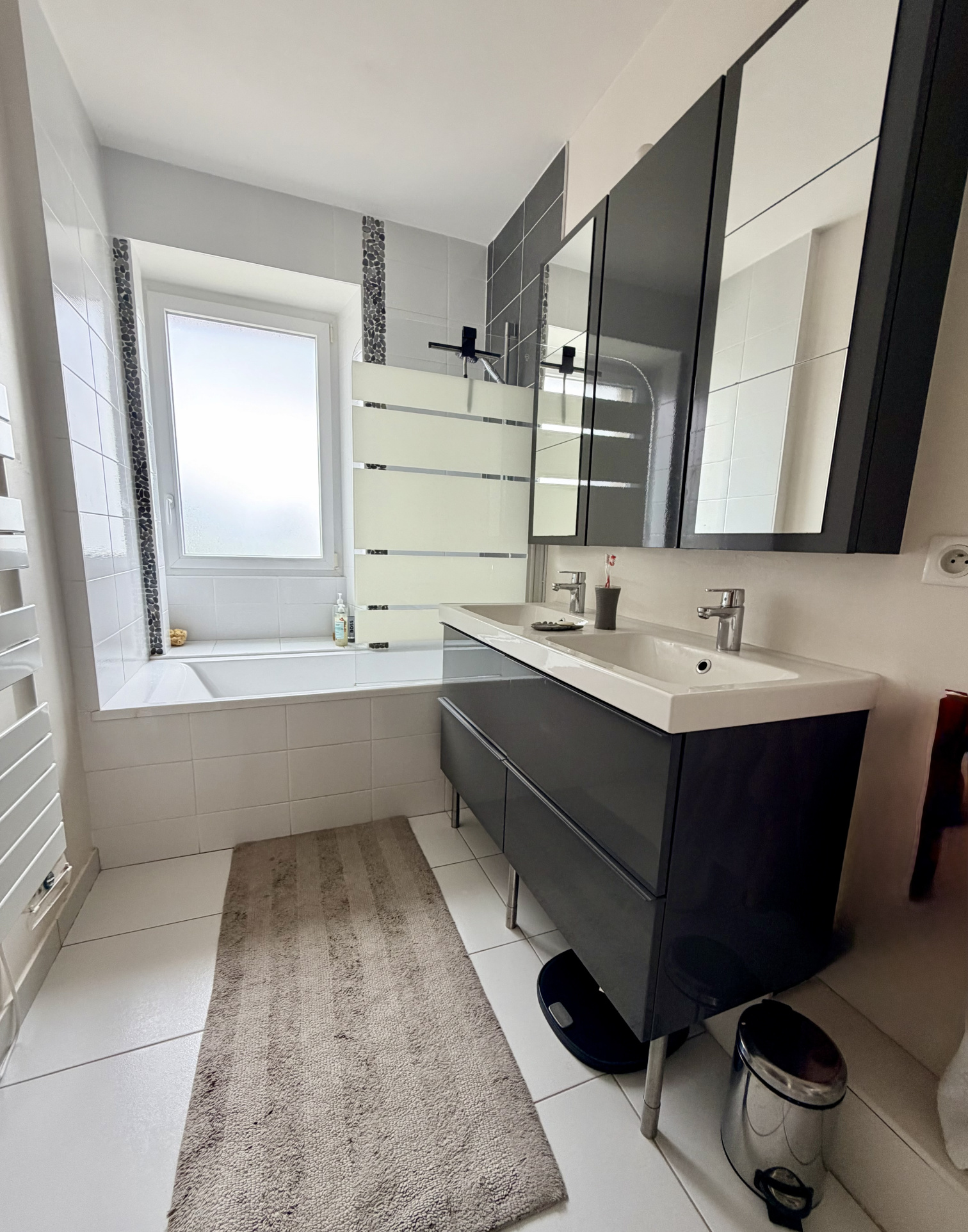 Salle de bain moderne avec baignoire, lavabo et miroir, dans une maison rénovée à Auray.
