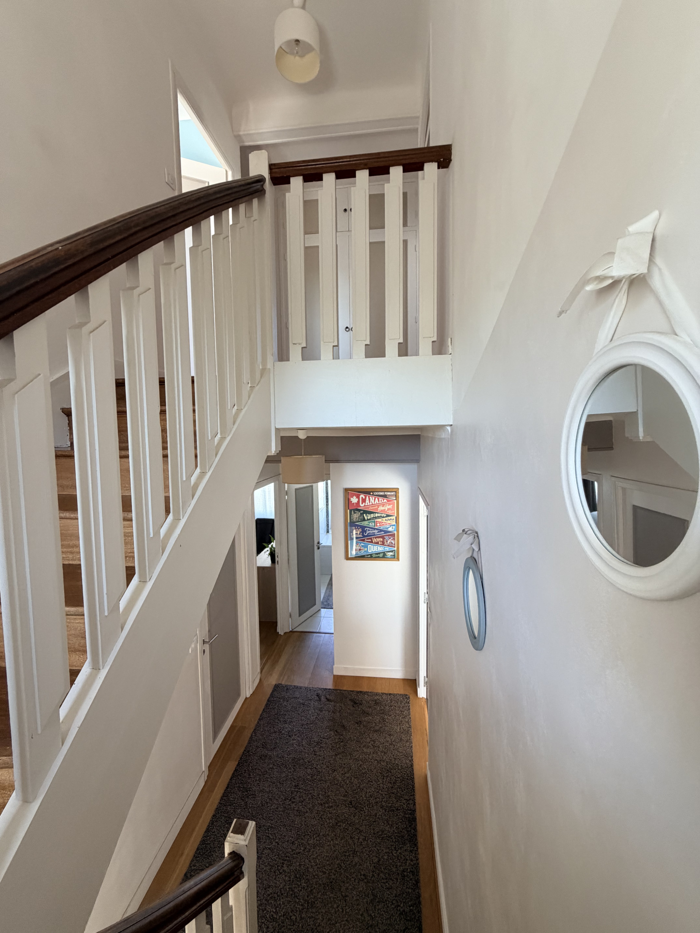 Vue intérieure d'une maison rénovée avec un escalier et un couloir lumineux.