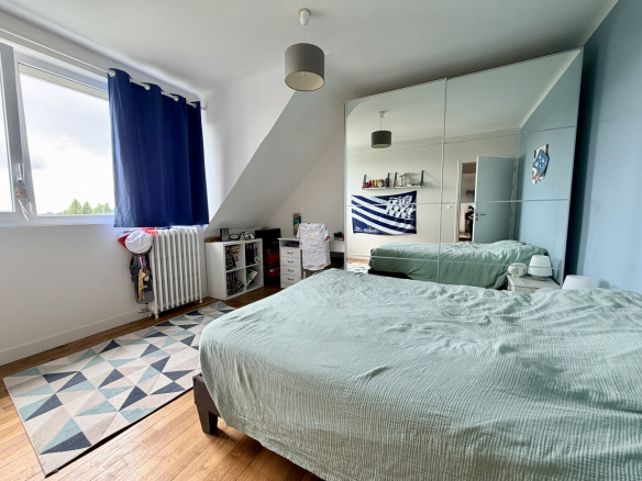 Chambre avec lit double, miroir, et décoration moderne dans une maison rénovée à Auray.