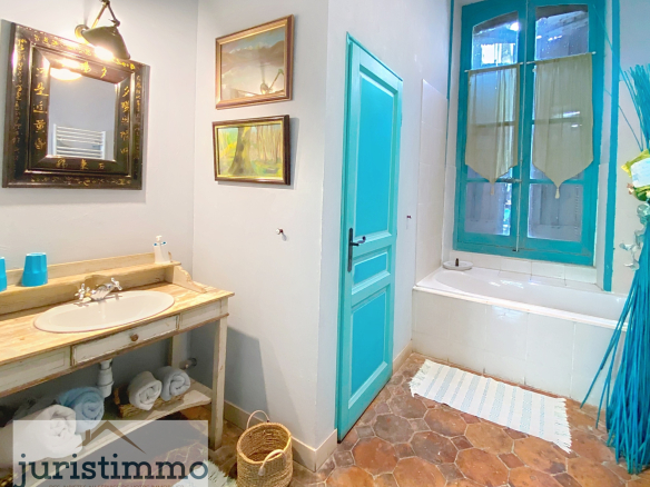 Bathroom with wooden sink and bathtub, light walls and blue windows.