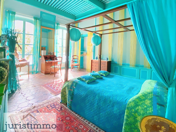 Colorful bedroom with a four-poster bed, desk and bright decor in a private mansion.