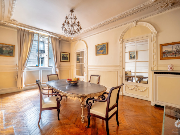 Interior of an elegant garden-level apartment with a round table and chairs, natural light coming in through the window.