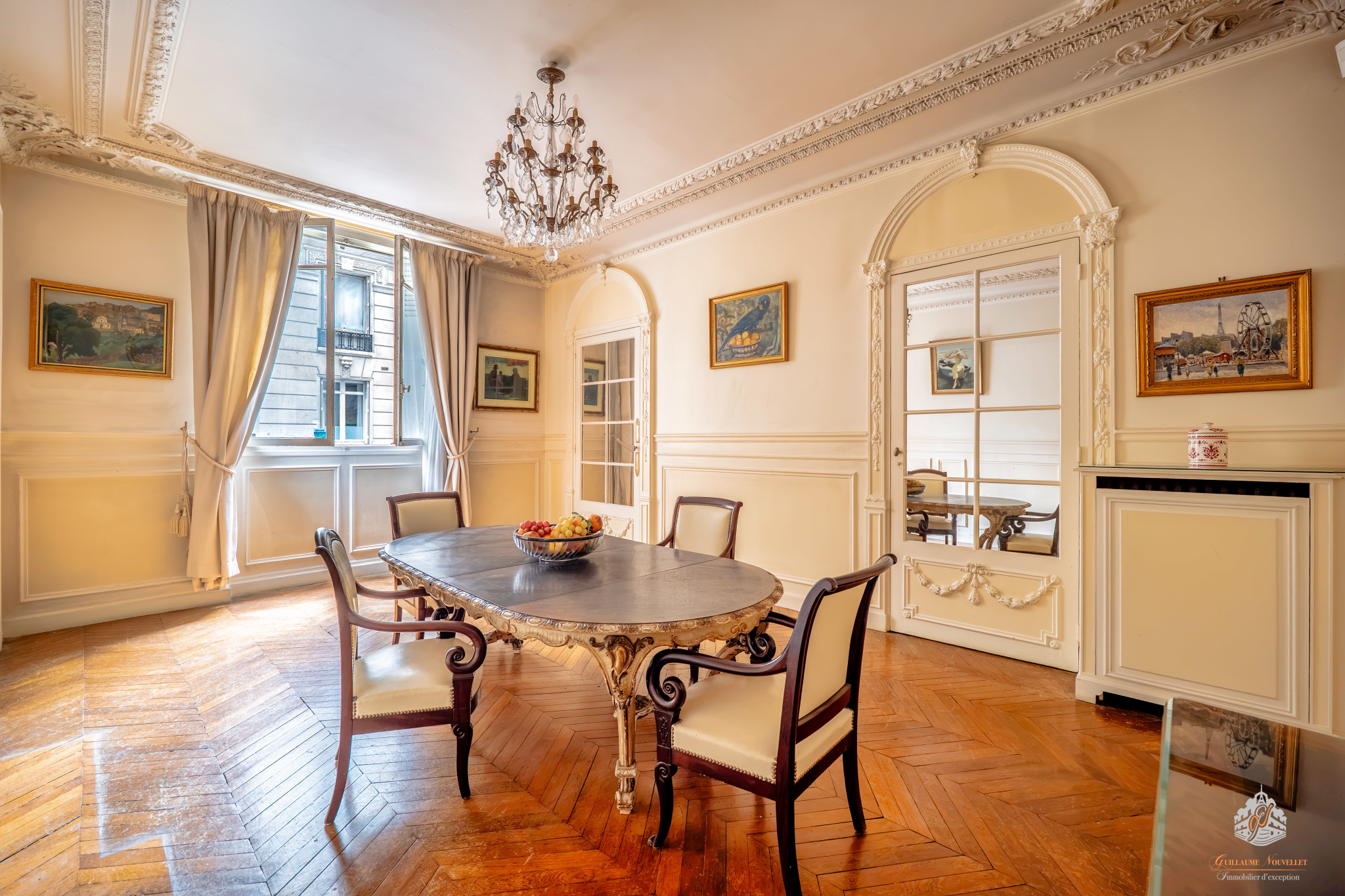 Interior of a ground-floor apartment in the 17th arrondissement of Paris Interior of an elegant garden-level apartment with a round table and chairs, natural light coming in through the window.