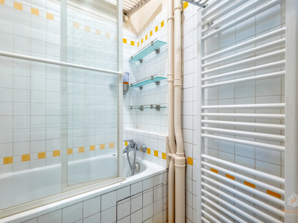 Bathroom with bathtub, white tiles and glass elements.
