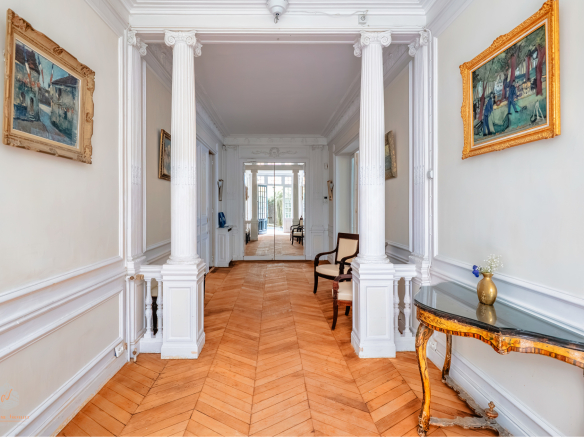 Interior of an elegant garden-level apartment with a bright hallway and decorative columns.