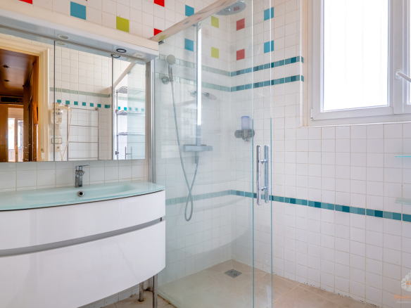 Modern bathroom with glass shower and colorful tiles.