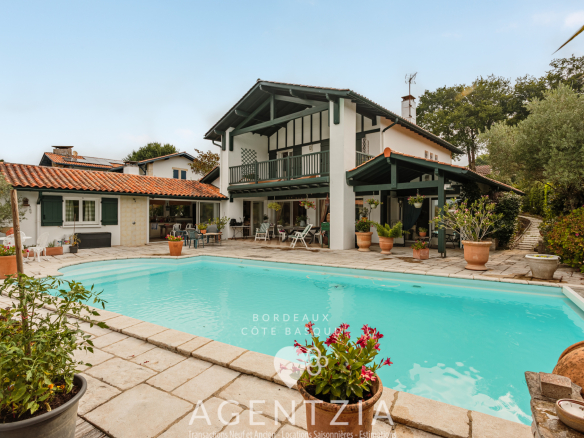 Villa de standing avec piscine et jardin à Bassussarry, entourée de verdure.